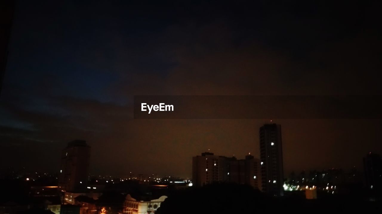 Illuminated buildings in city against sky at night