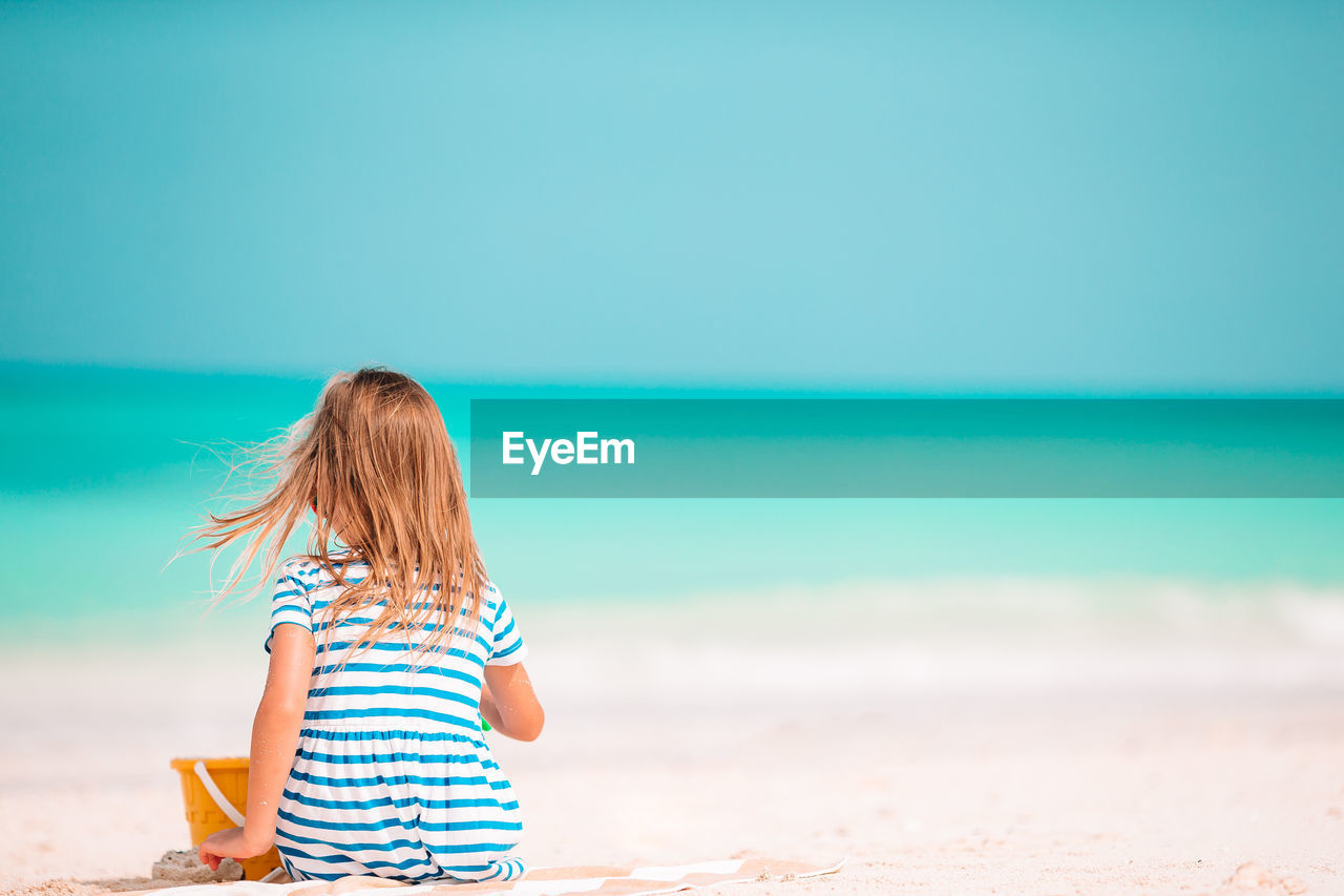 REAR VIEW OF WOMAN ENJOYING ON BEACH