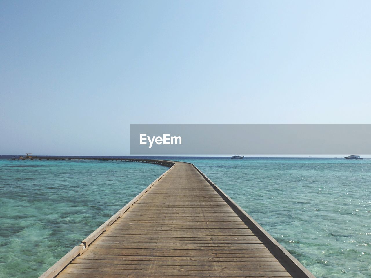 Empty pier over sea against clear sky