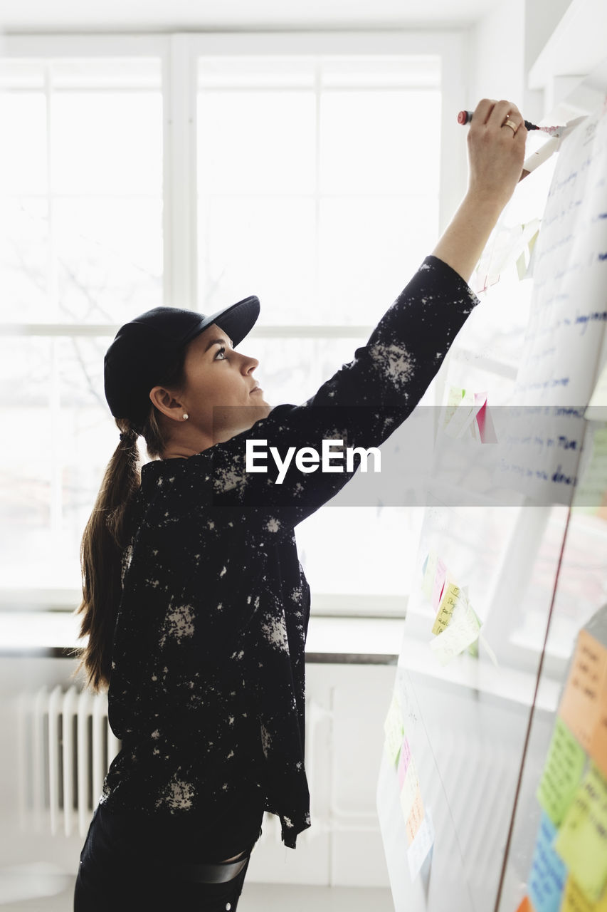 Businesswoman writing on whiteboard in creative office