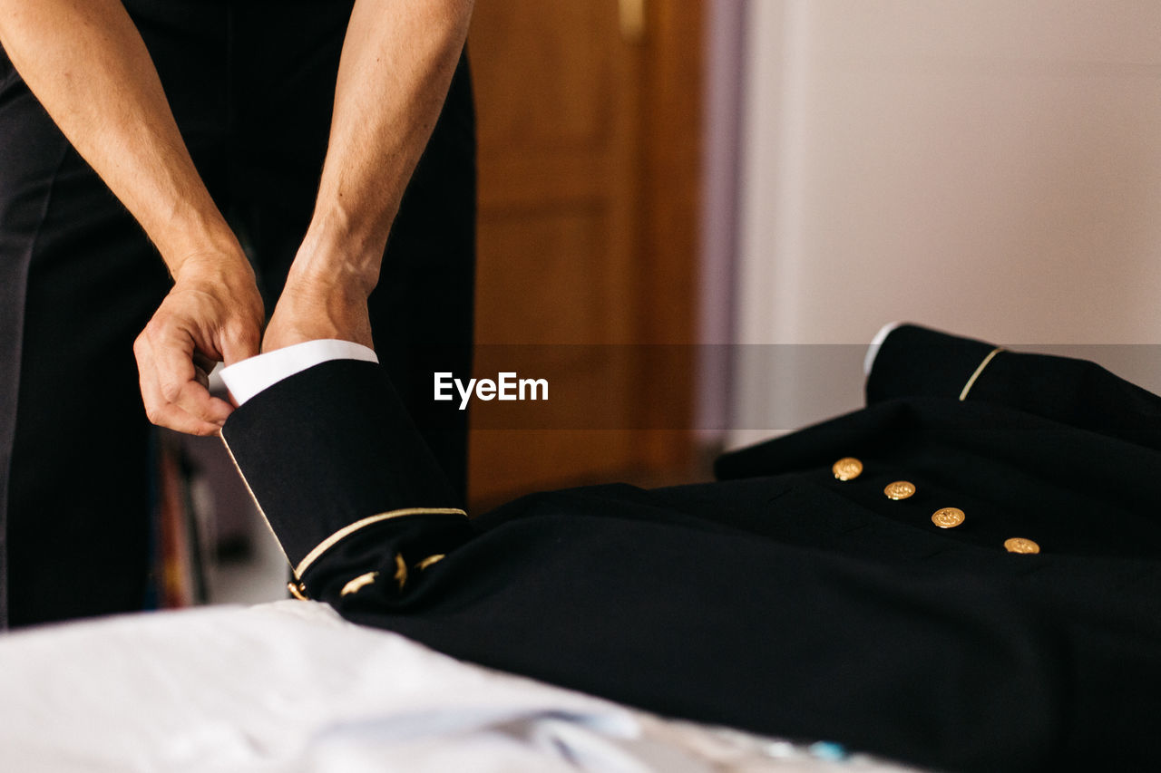 Cropped hand of man adjusting suit at home