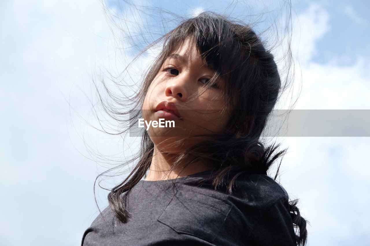 Low angle portrait of girl against sky