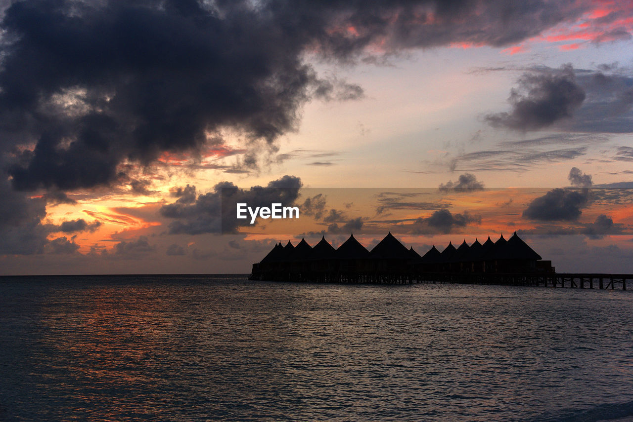 Scenic view of sea against cloudy sky at sunset