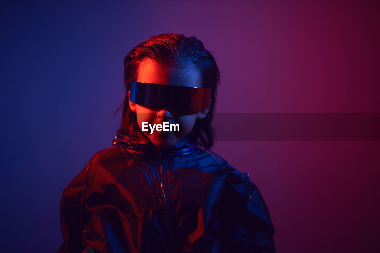 Portrait cyberpunk boy child in vr glasses in blue and red tones. game, virtual reality