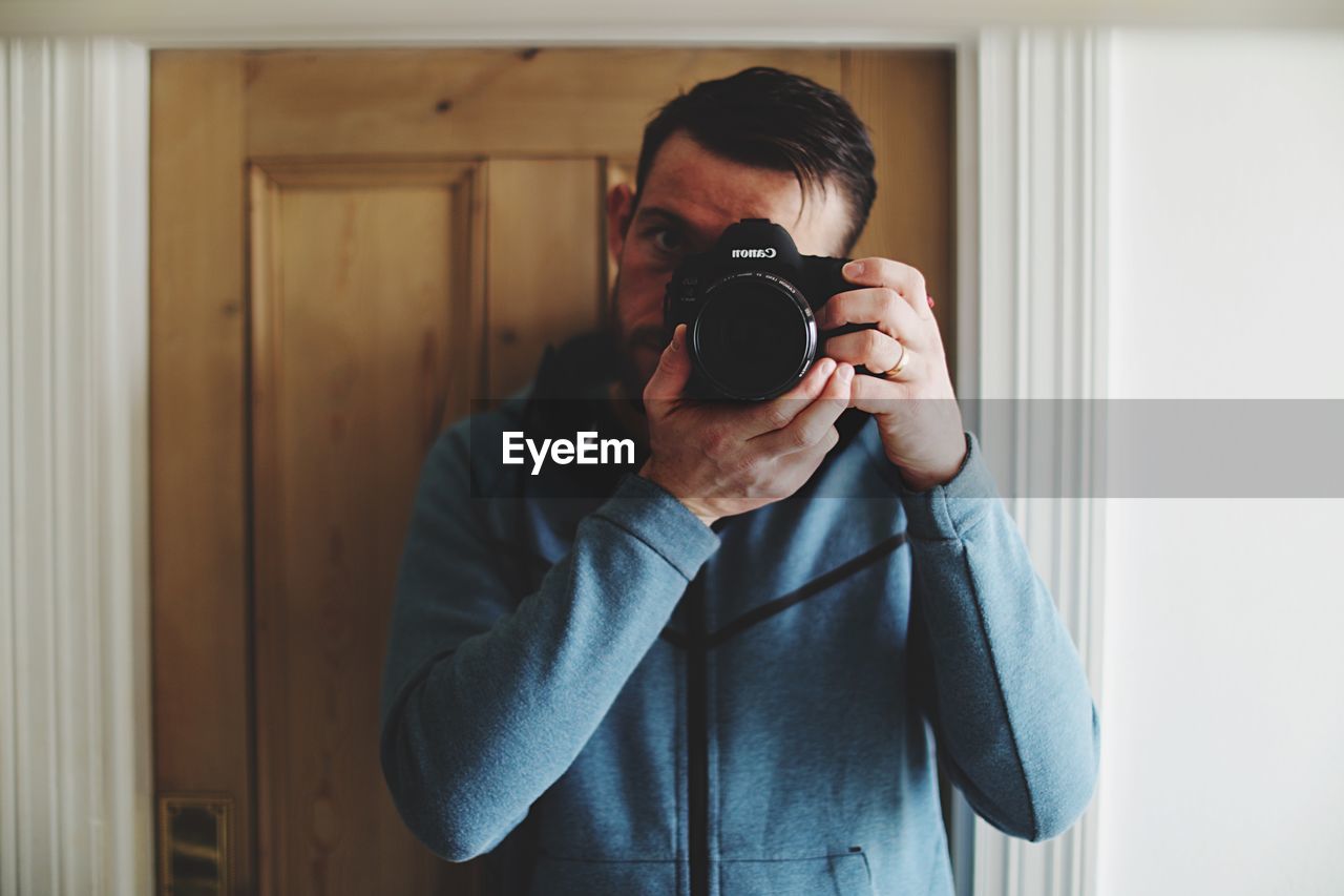 PORTRAIT OF YOUNG MAN PHOTOGRAPHING WITH CAMERA