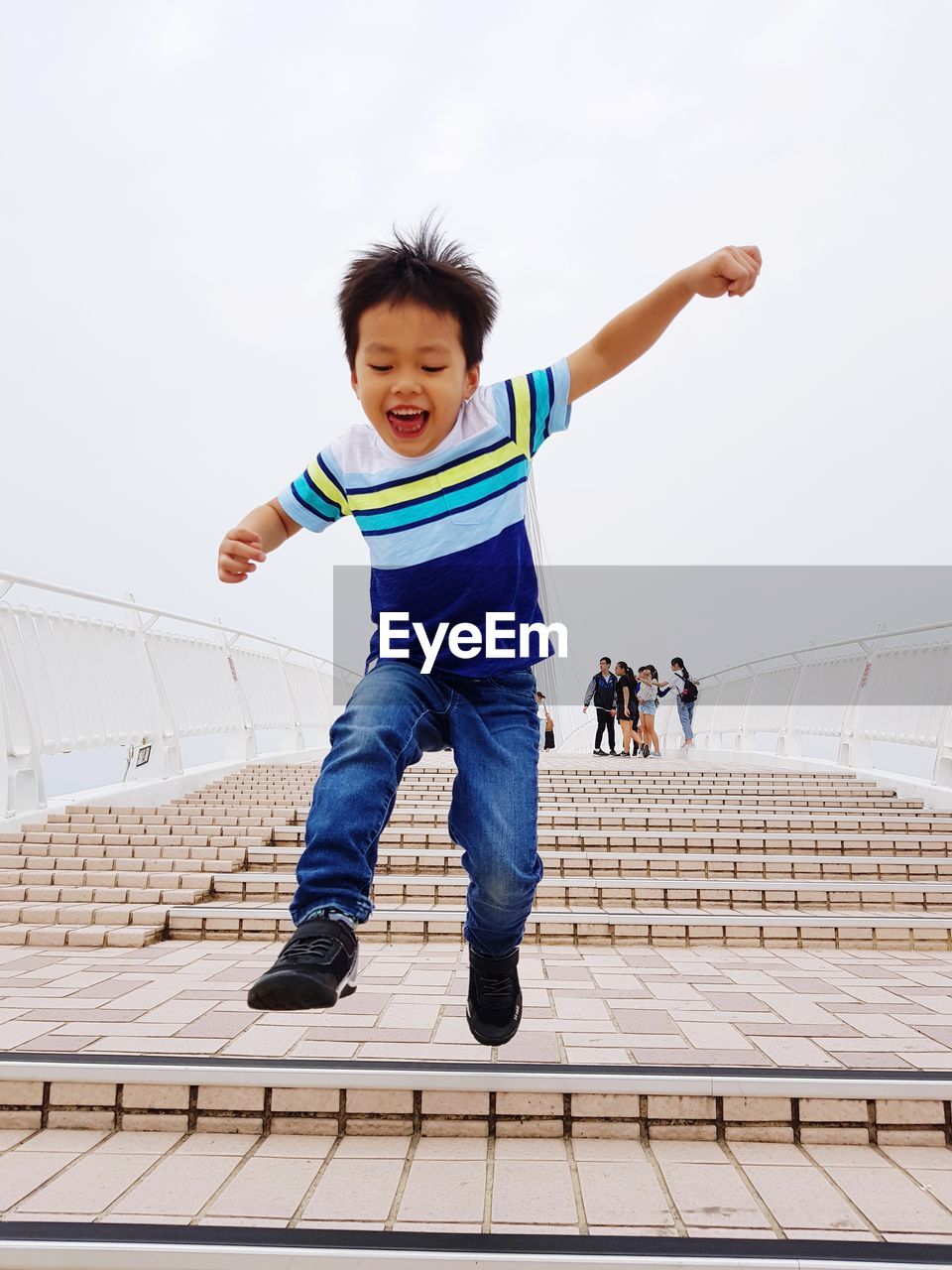 Full length of cheerful boy jumping on steps