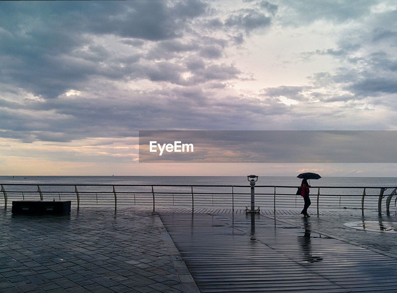 Man standing on pier over sea against sky