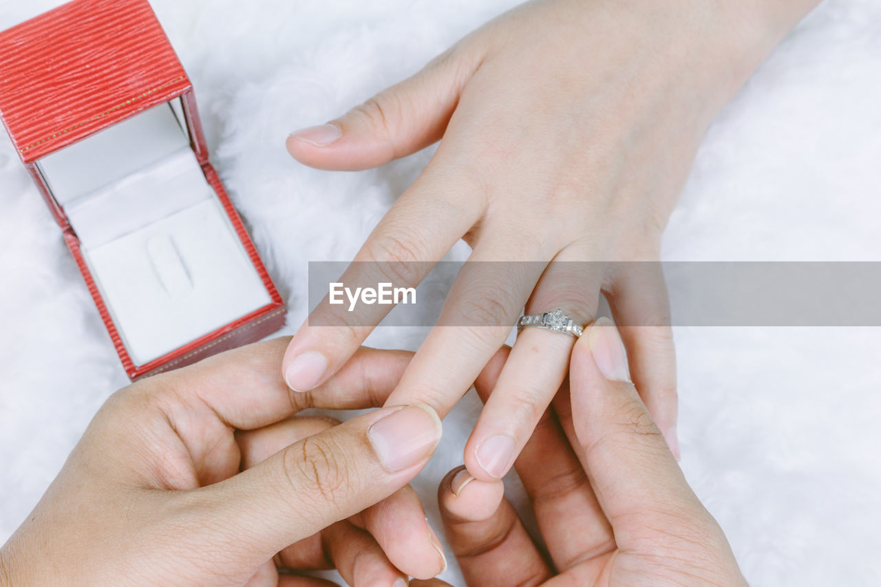 Cropped hands of man inserting diamond ring in woman finger