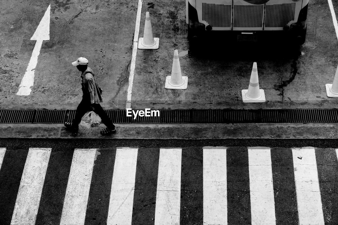 High angle view of man walking by zebra crossing
