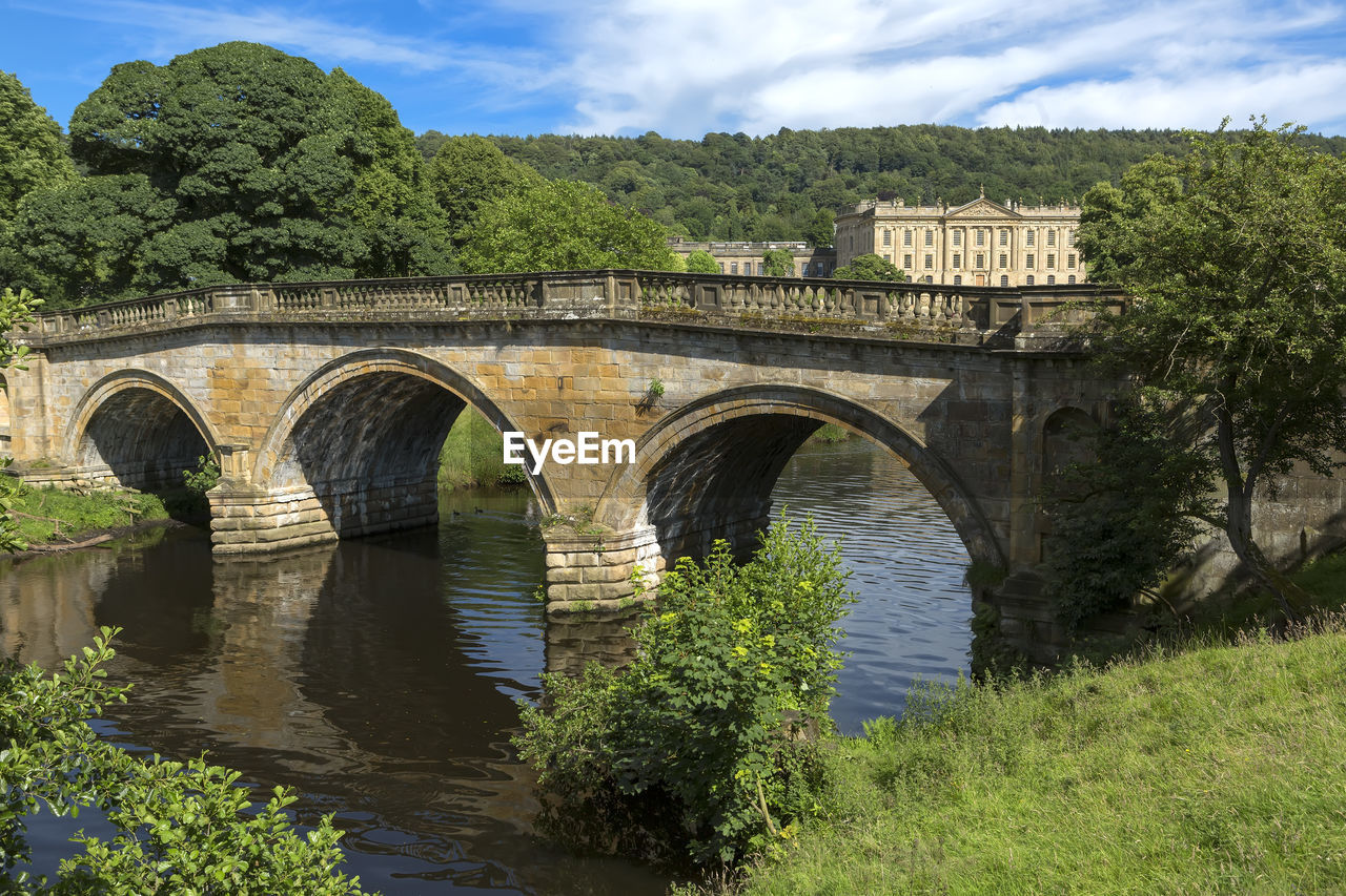 ARCH BRIDGE OVER RIVER AGAINST TREES