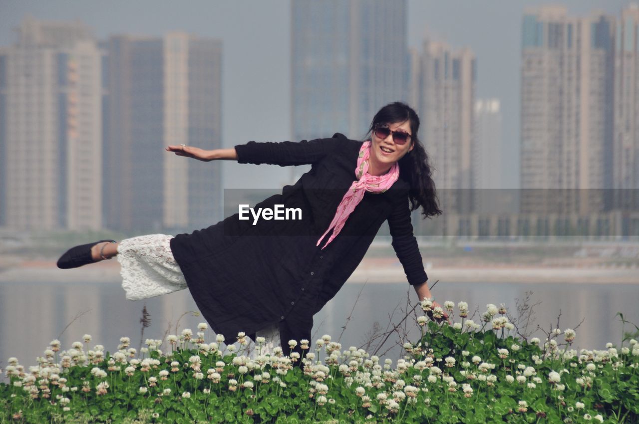 Portrait of woman standing on field against buildings