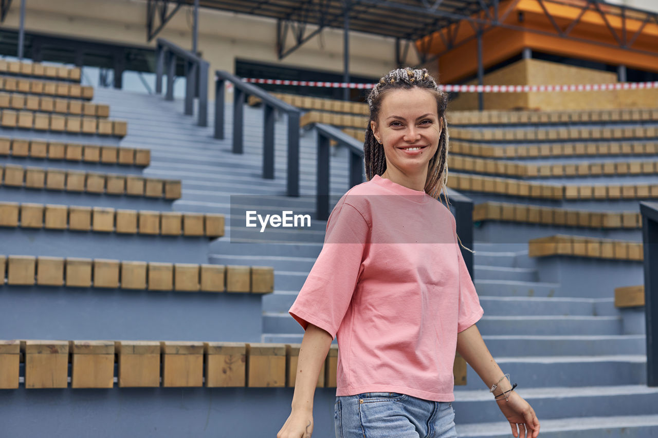 Portrait of smiling woman standing against staircase