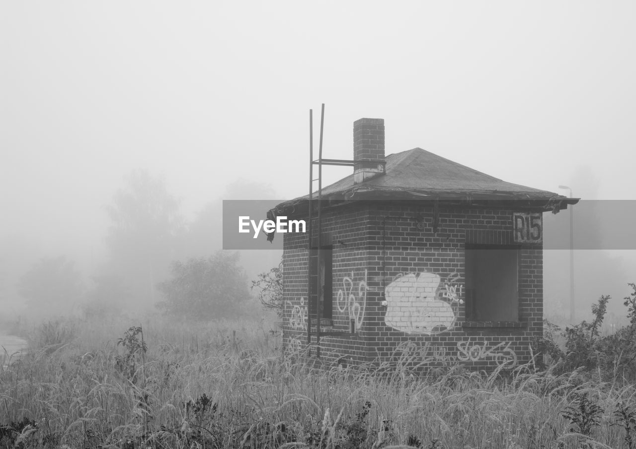 Old build structure on grassy field during foggy weather