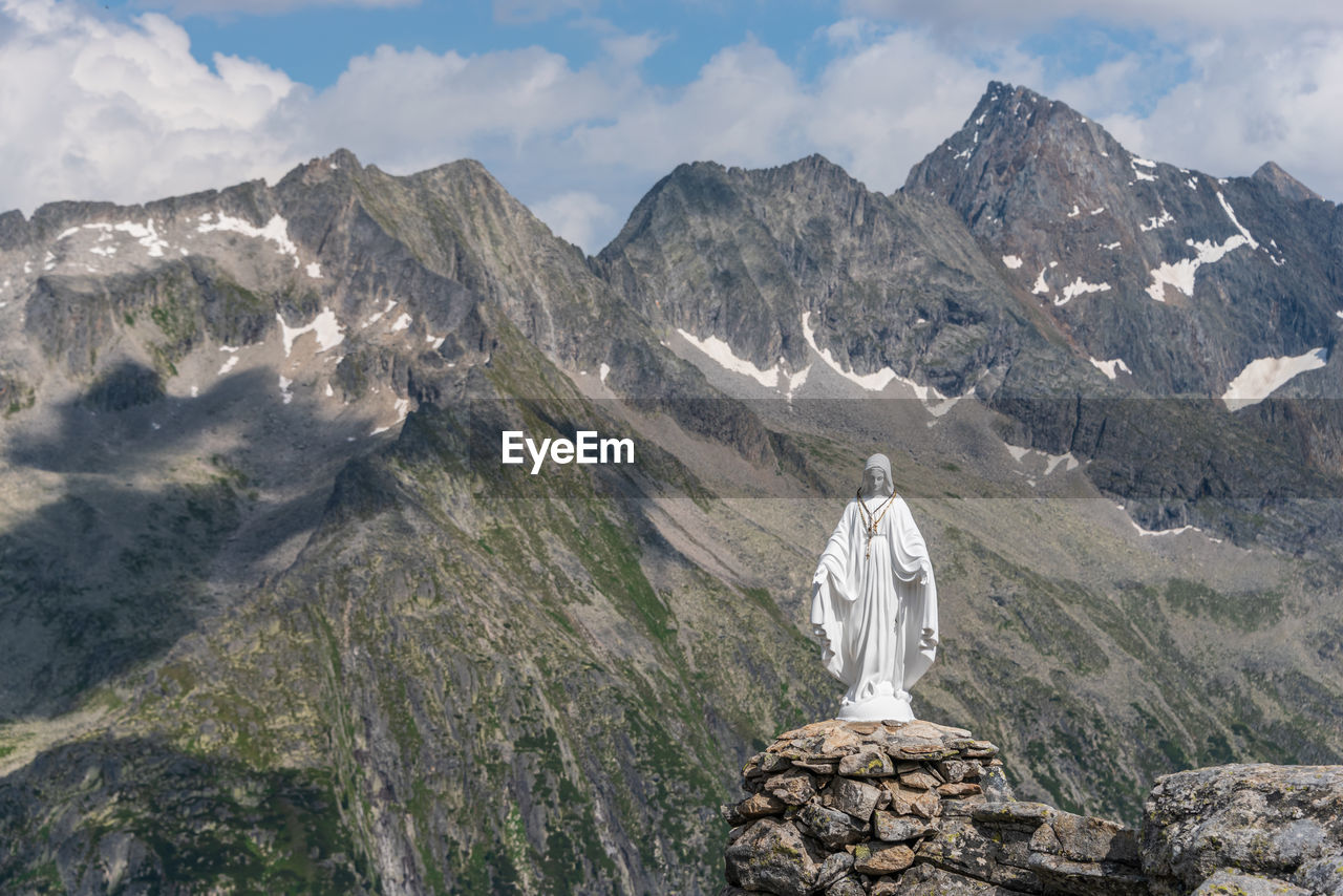 White statue of virgin mary, mother of god, placed on top of the mountain in background