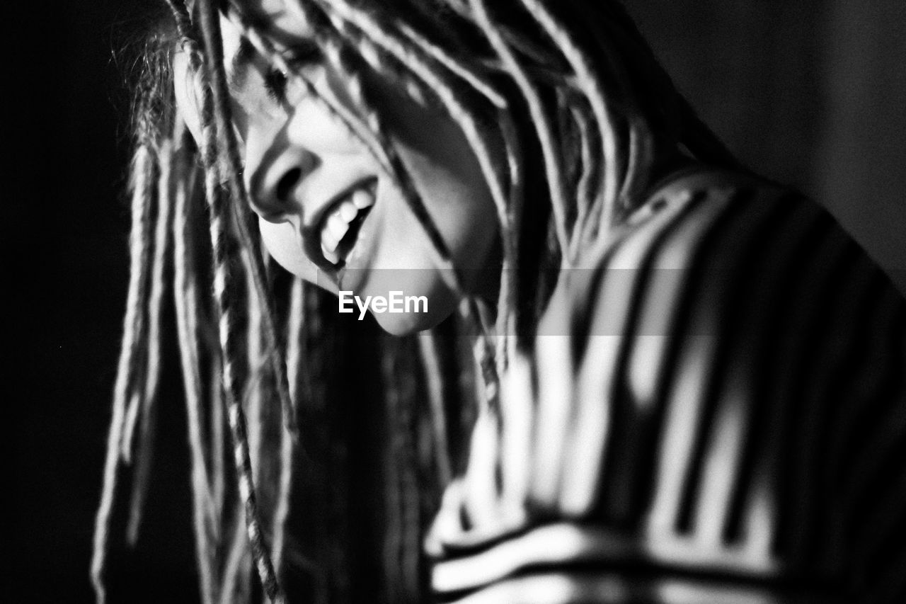 Close-up of cheerful woman with dreadlocks in darkroom