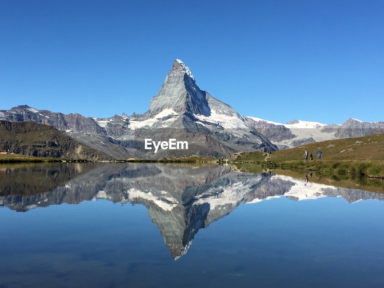 Reflection of mountains and lake against clear blue sky