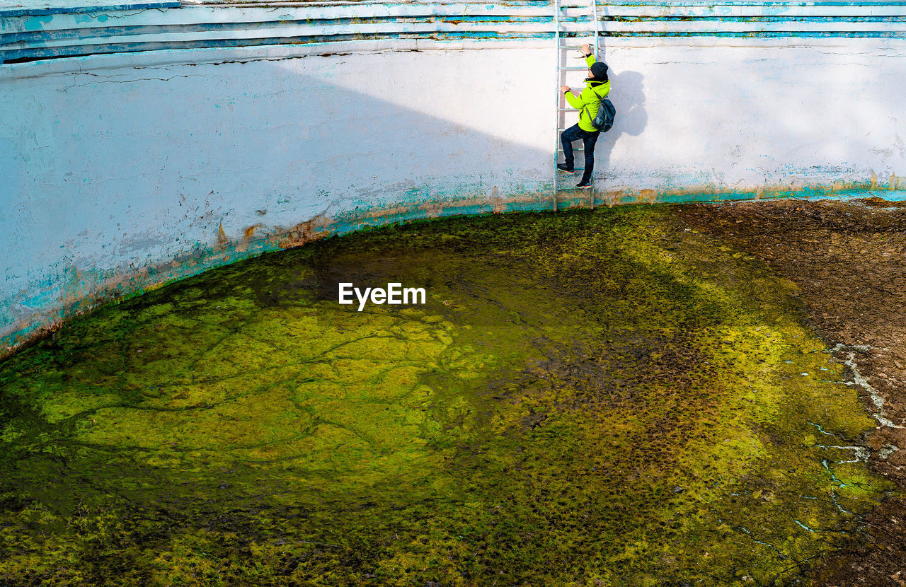 Man climbing stairs of abandoned dirty pool