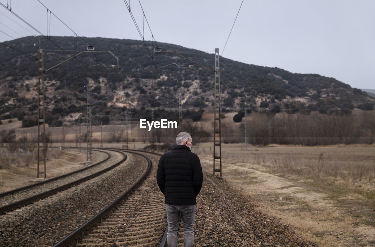Adult man in warm clothing with railway in countryside. shot in castilla la mancha, spain