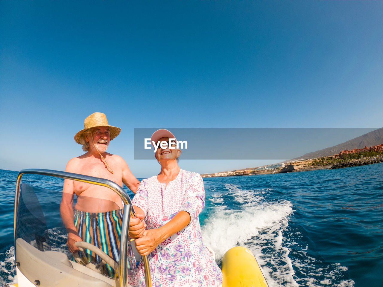 Senior couple on motorboat in sea against sky