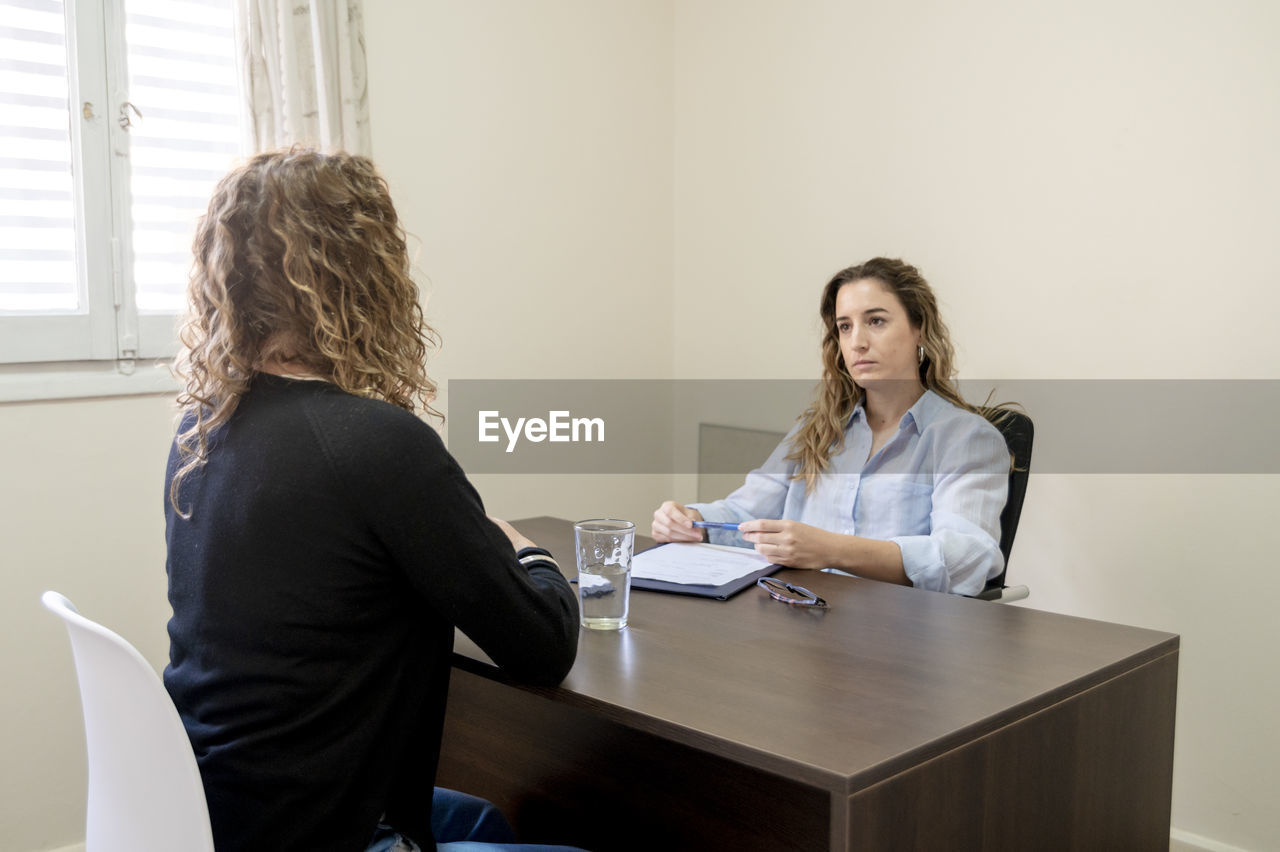 Professional female psychologist listening to her patient during therapy session at her office.