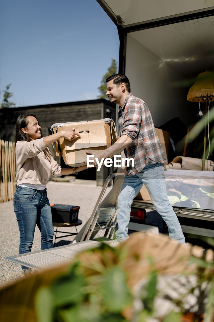 Couple unloading box from truck while relocating to new house