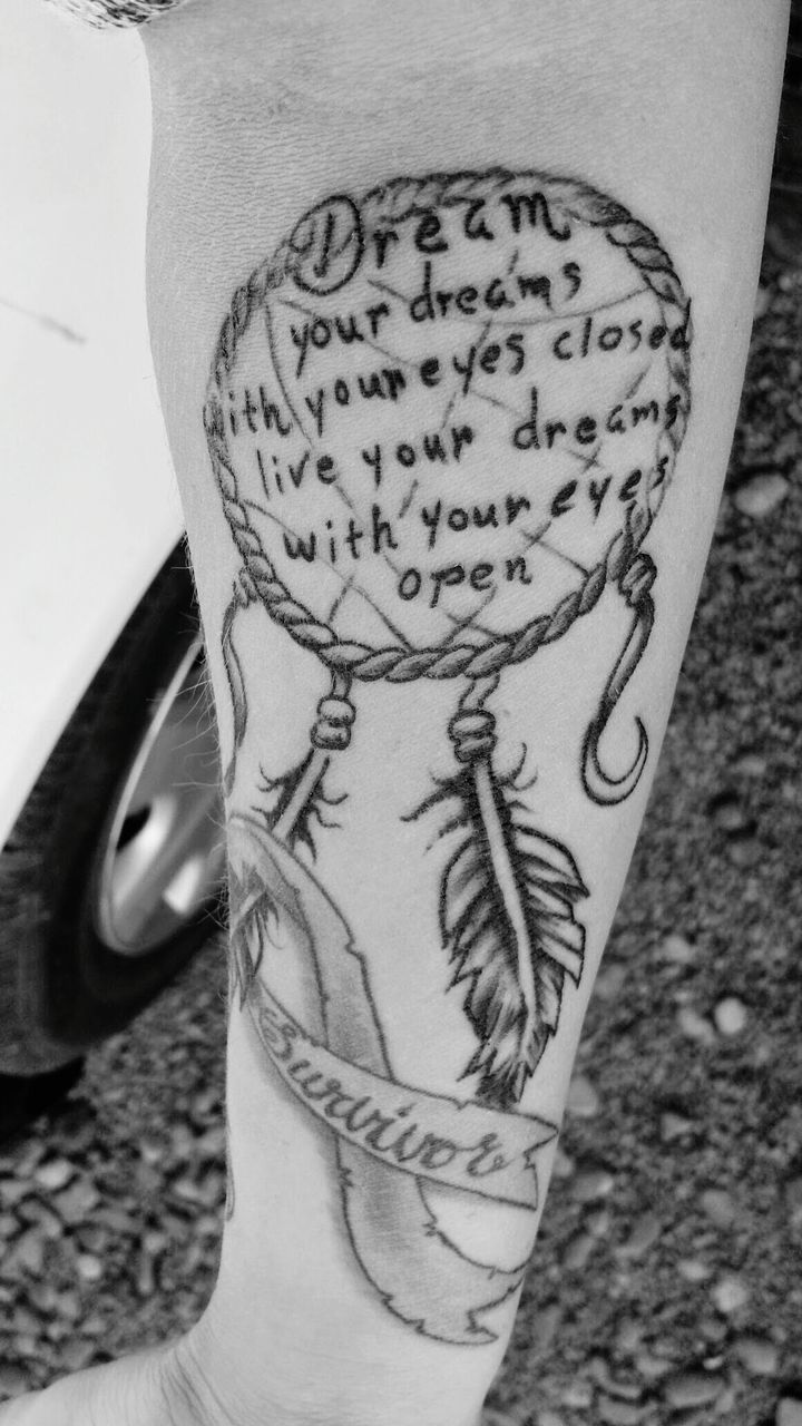 Cropped image of hand with dreamcatcher tattoo and text