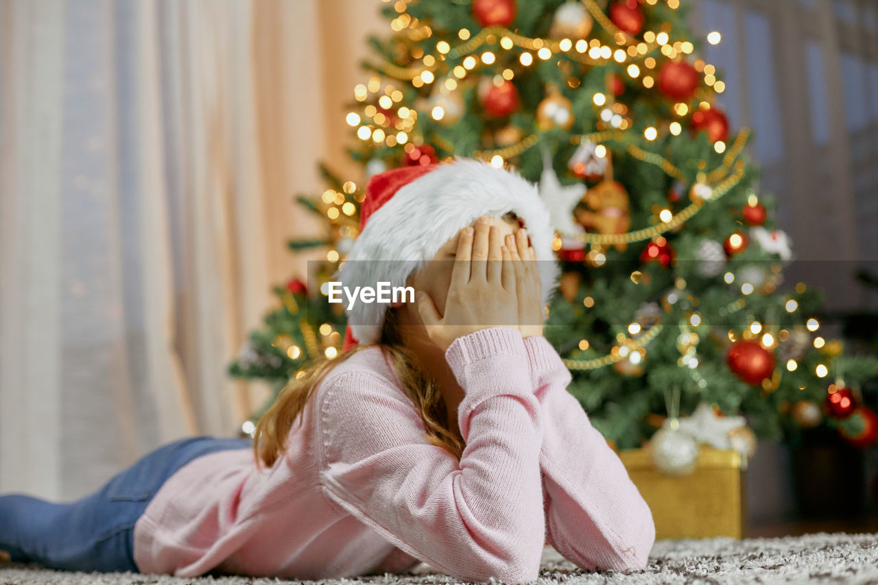 A cute girl lies by the christmas tree and dreams. dreams come true. children waiting new year