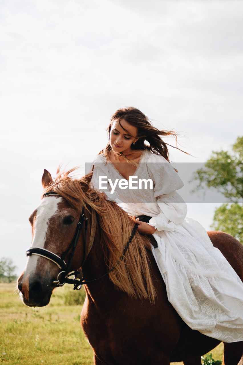 Young woman riding horse on field