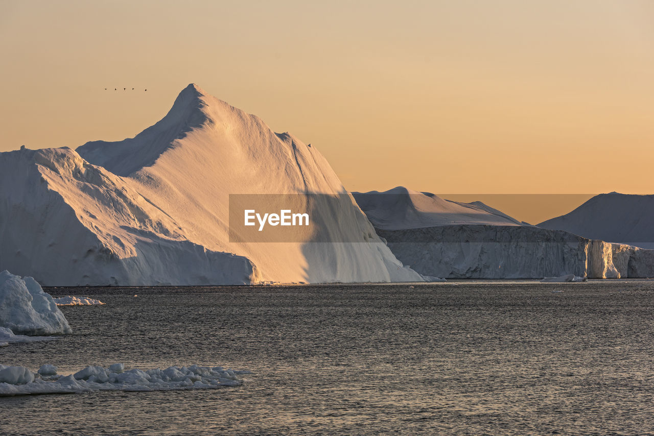 Idyllic shot of ice formations in sea against sky during sunset