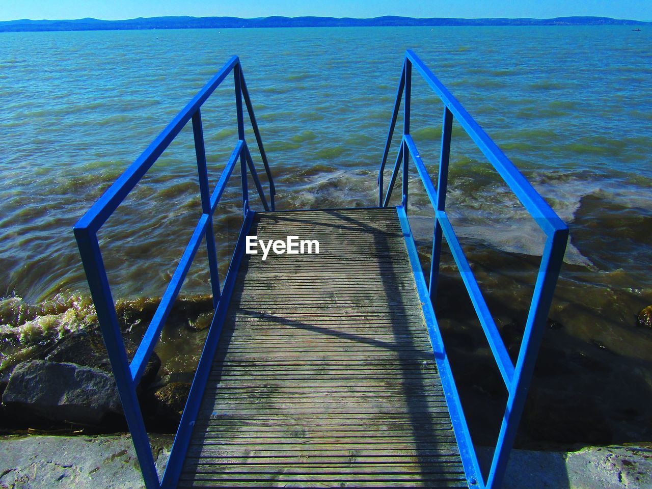 CLOSE-UP OF RAILING AT BEACH AGAINST SKY