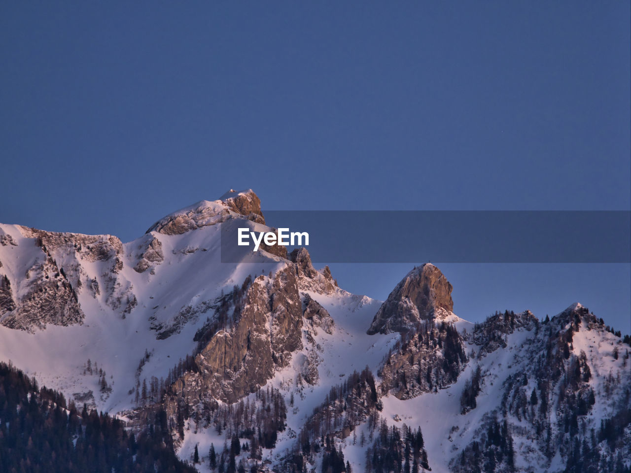 Scenic view of snowcapped mountains against clear blue sky at dusk