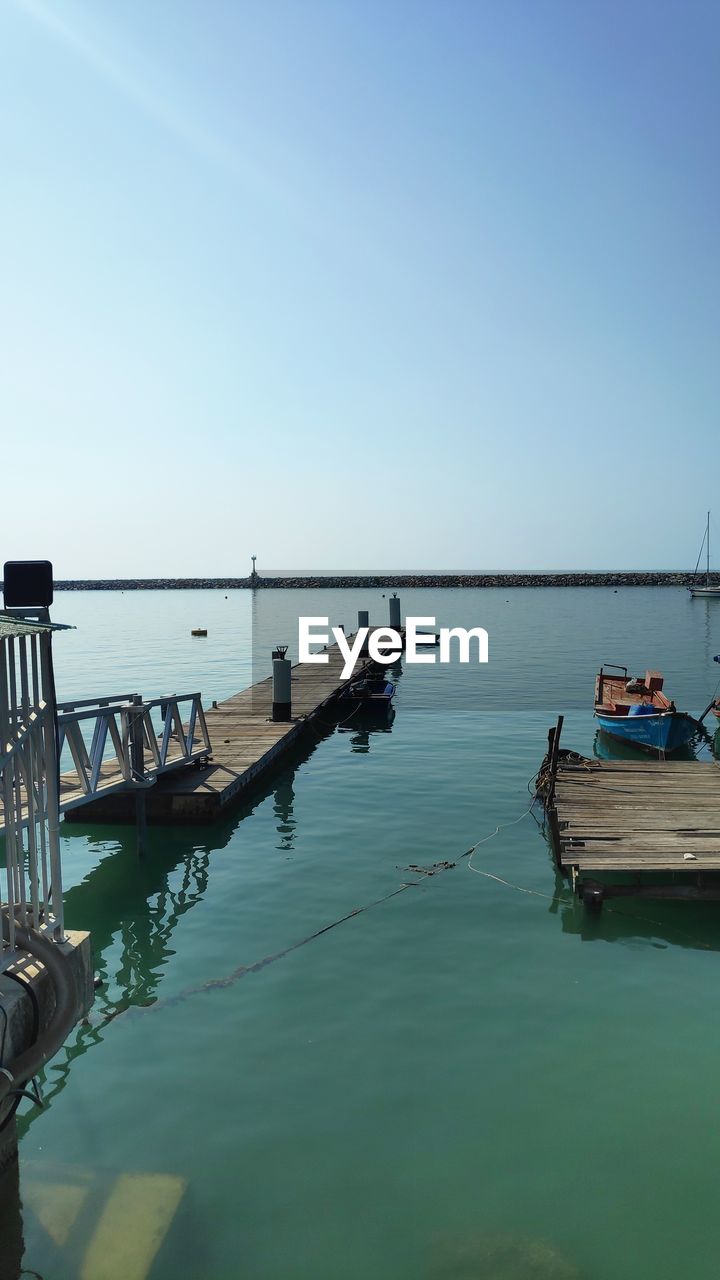 BOATS MOORED IN SEA AGAINST CLEAR SKY