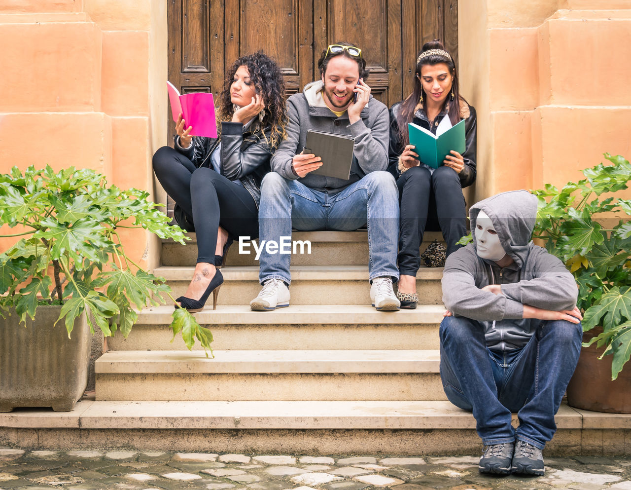 Male and female friends sitting on steps at entrance of building