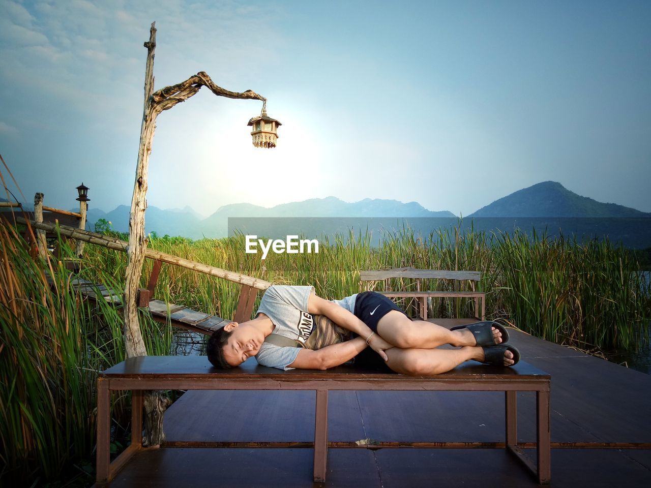 YOUNG MAN LYING ON FARM AGAINST SKY