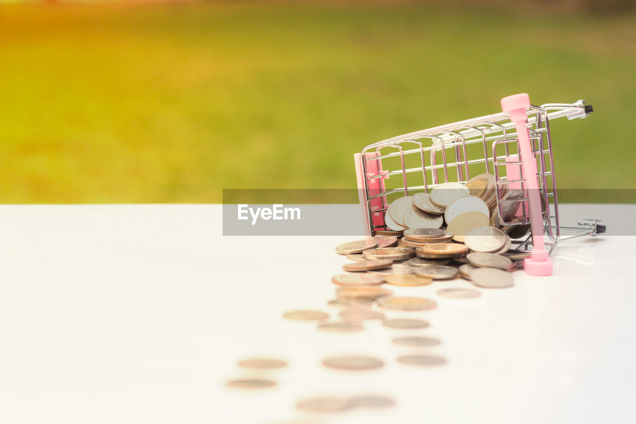 Close-up of small shopping cart and coins on table