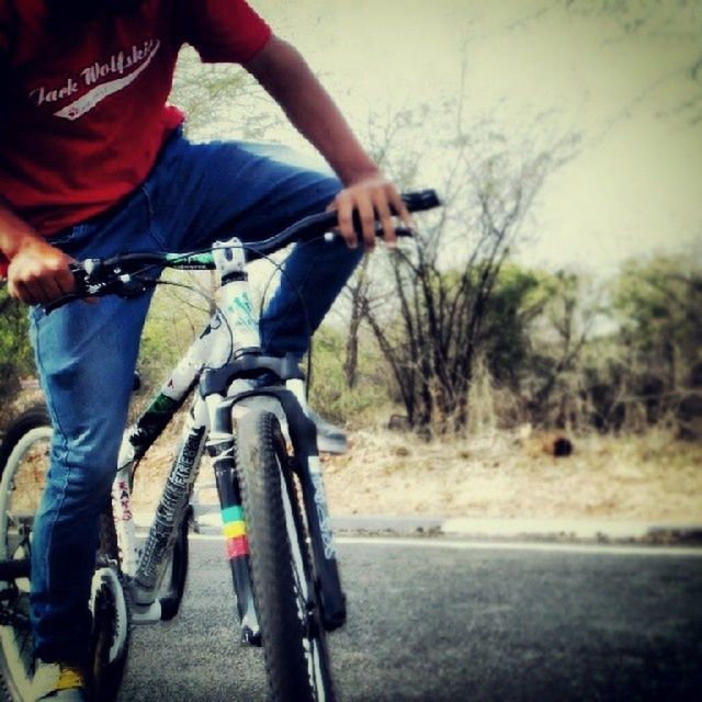 REAR VIEW OF MAN CYCLING ON ROAD