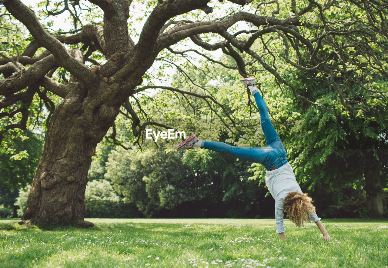 Woman doing handstand on grassy field