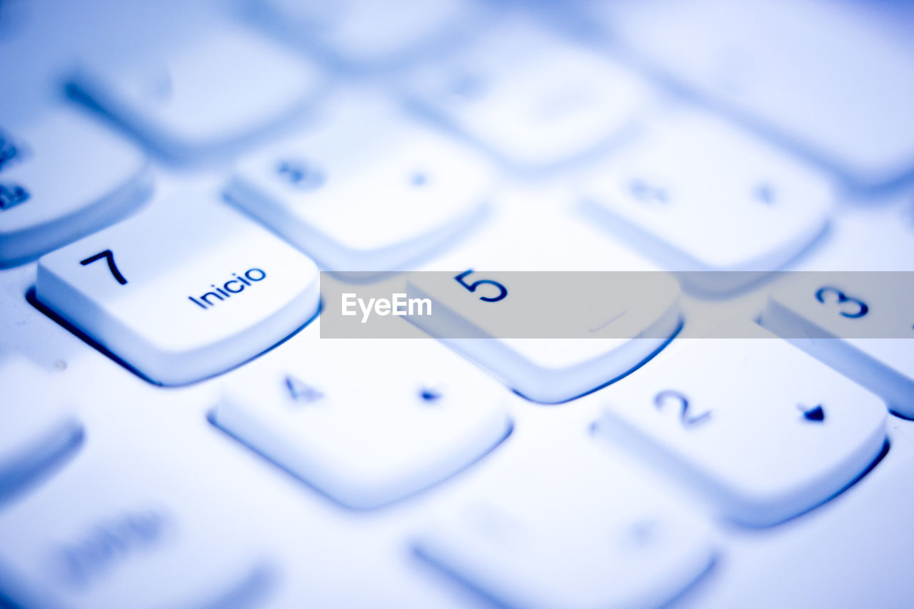 CLOSE-UP OF LAPTOP KEYBOARD AND BLUE COMPUTER