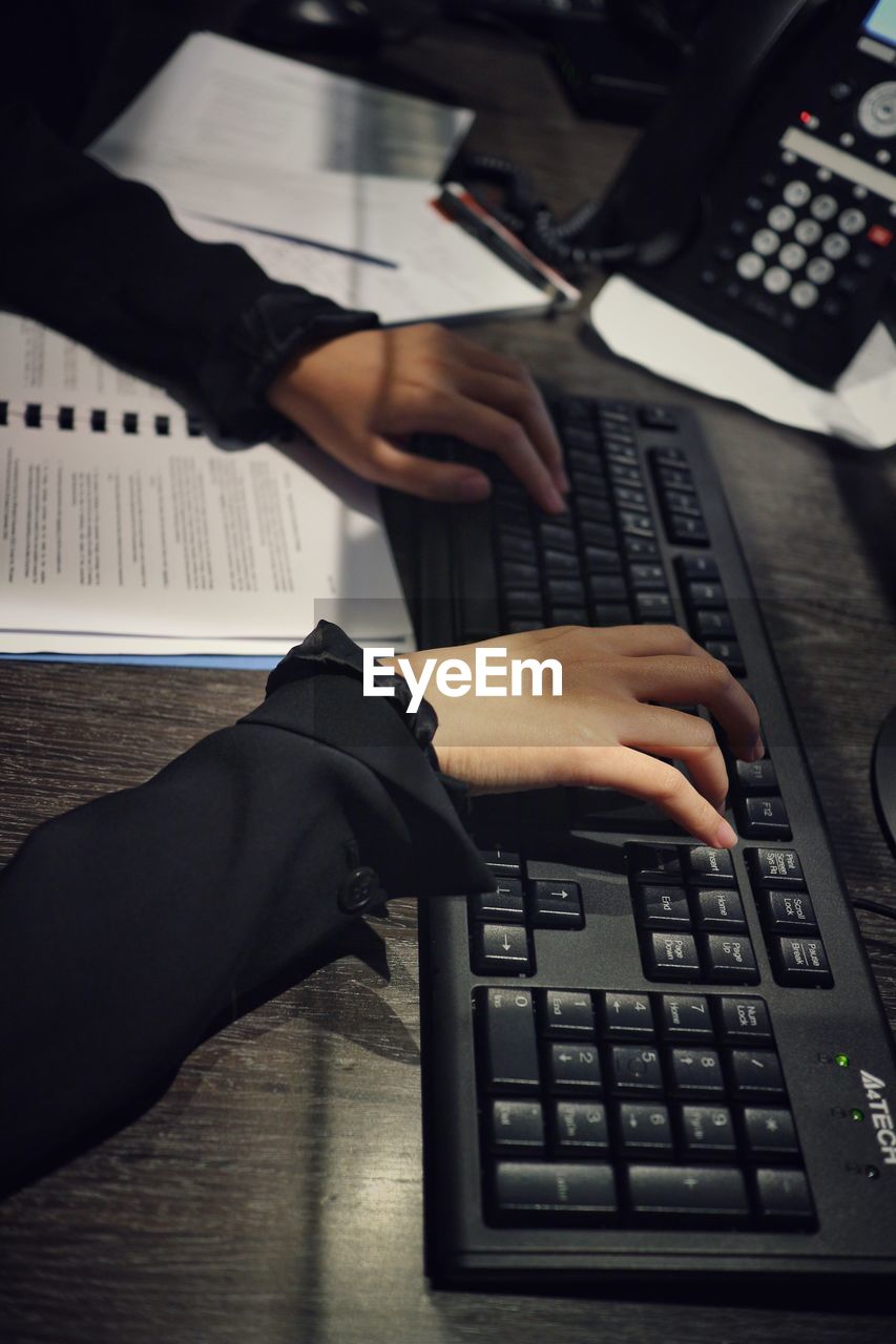 Cropped hands of businesswoman using computer in office