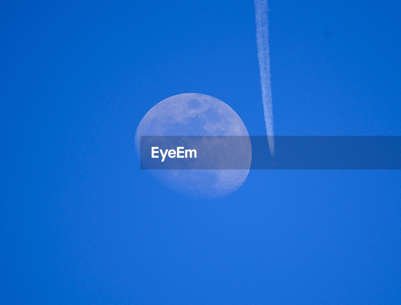 LOW ANGLE VIEW OF MOON IN BLUE SKY