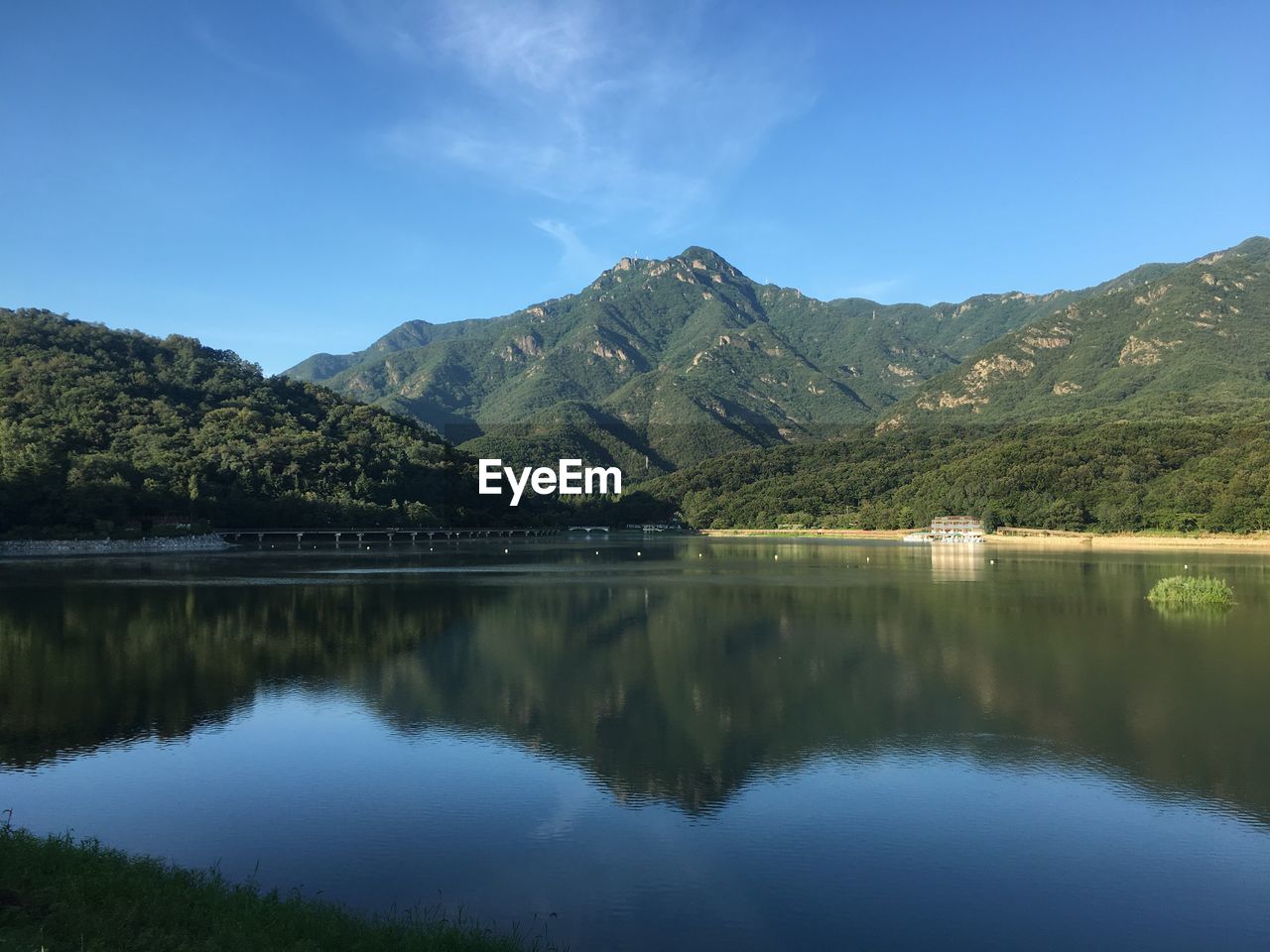 Scenic view of lake and mountains against clear blue sky