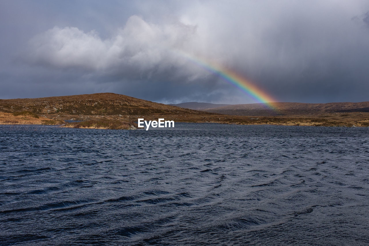 Scenic view of rainbow over sea against sky