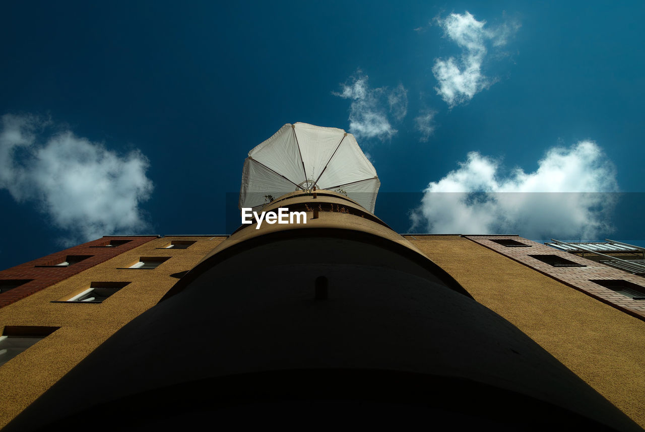Low angle view of parasol on building against sky
