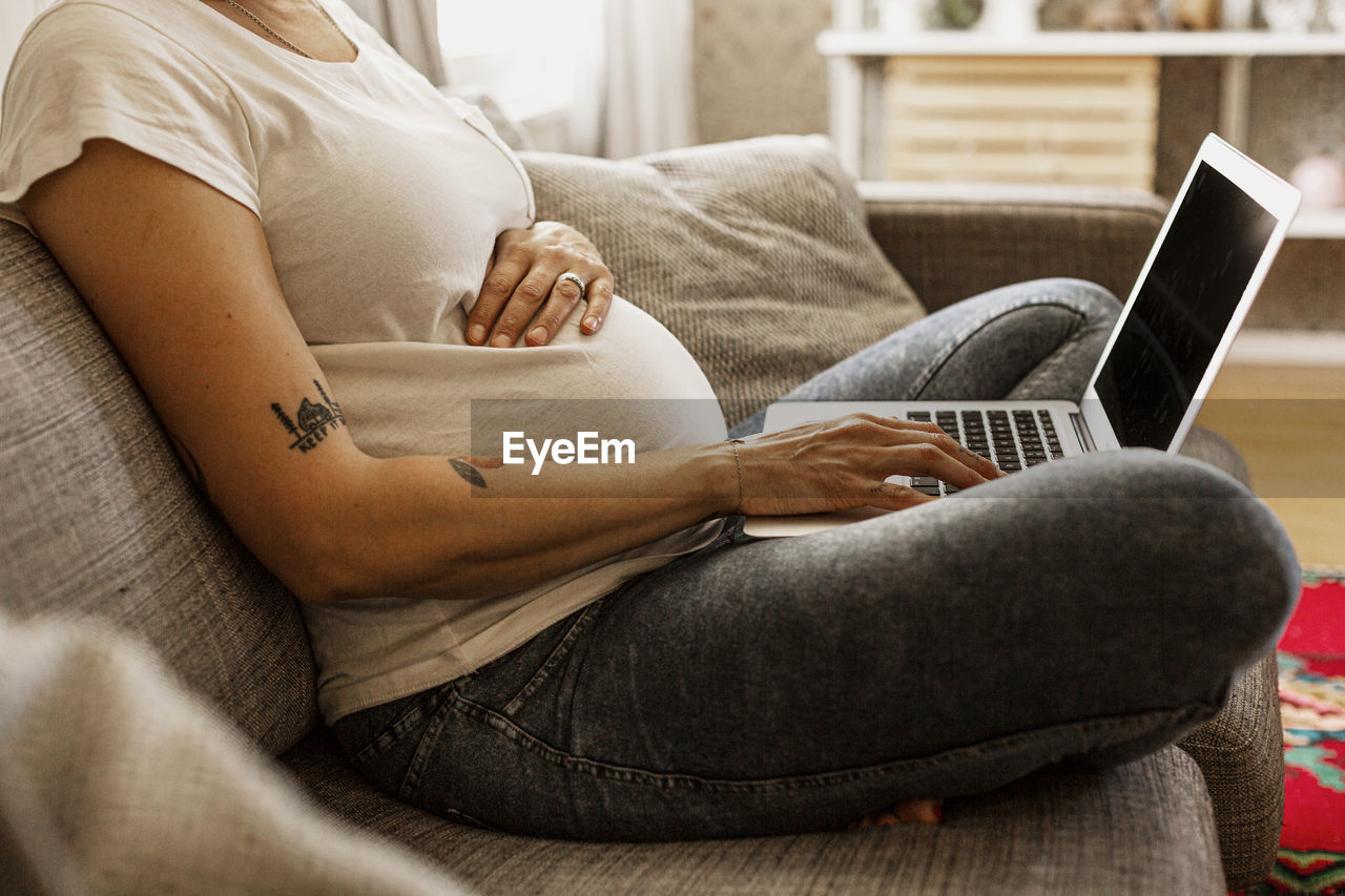 Mid section of pregnant woman using laptop