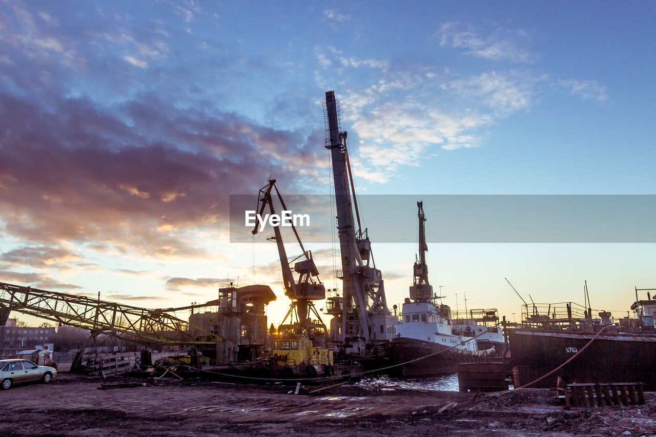 Cranes at harbor against sky