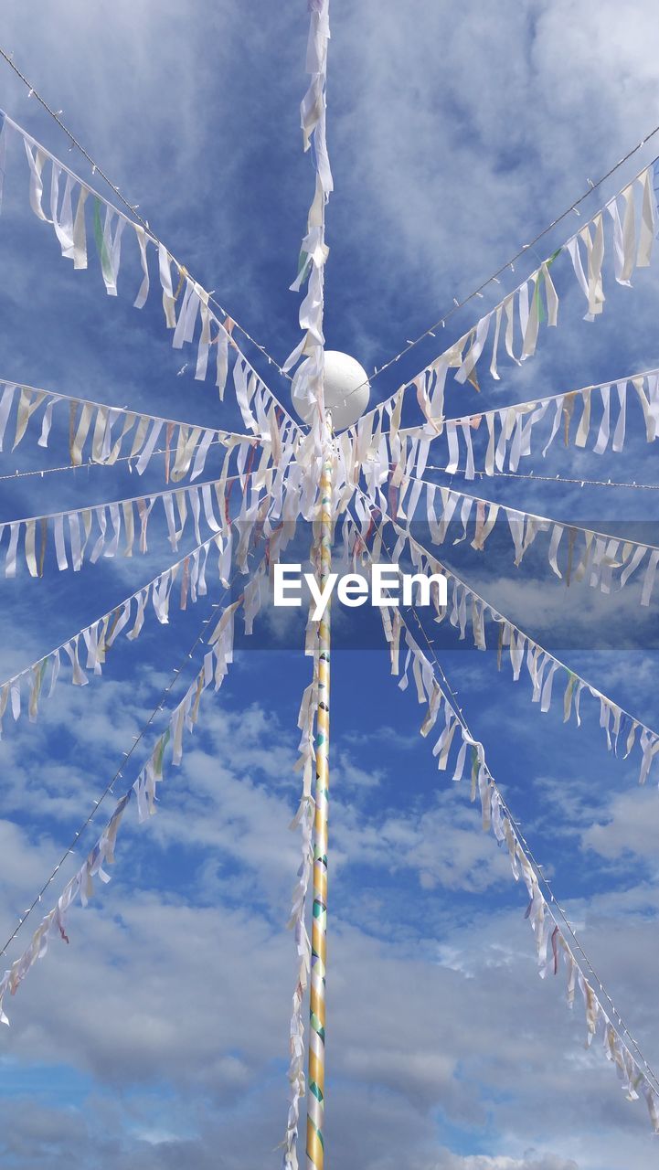 Low angle view of may pole with streamers, against clear blue sky