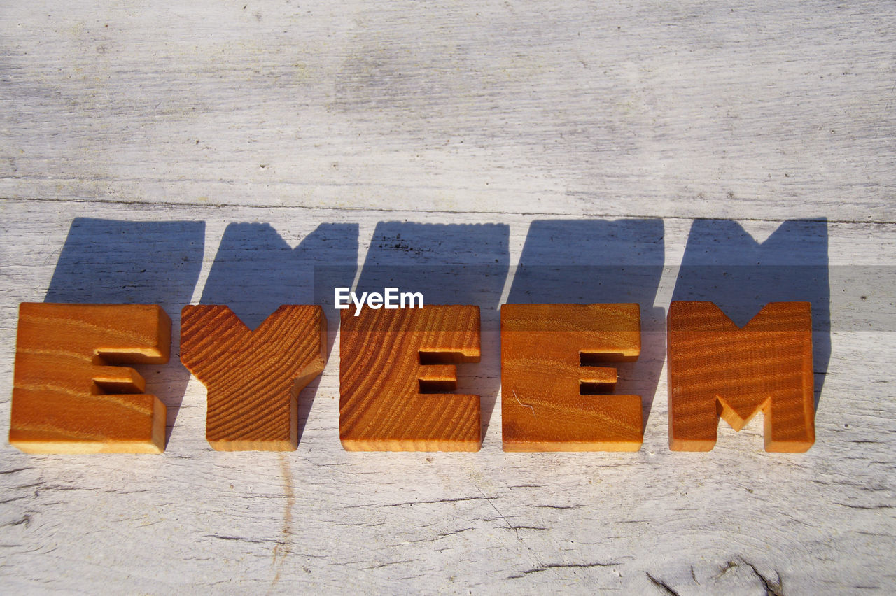 High angle view of eyeem text on table during sunny day