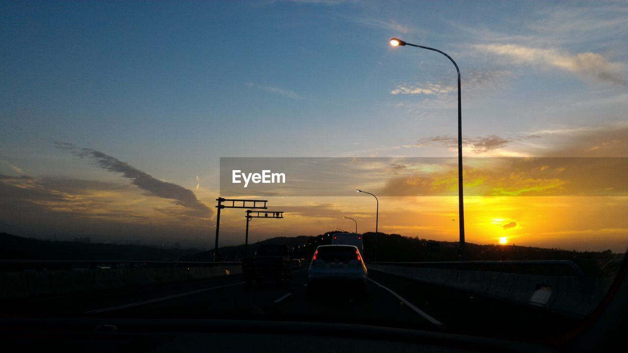 Car on highway against sky during sunset