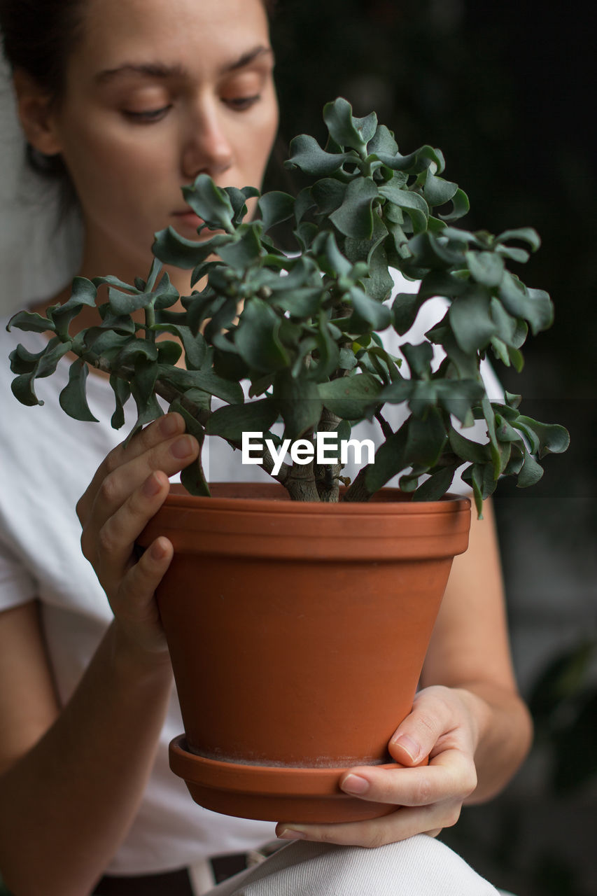 Close-up of woman gardener holding houseplant in her hands. love plants, hobby, home gardening