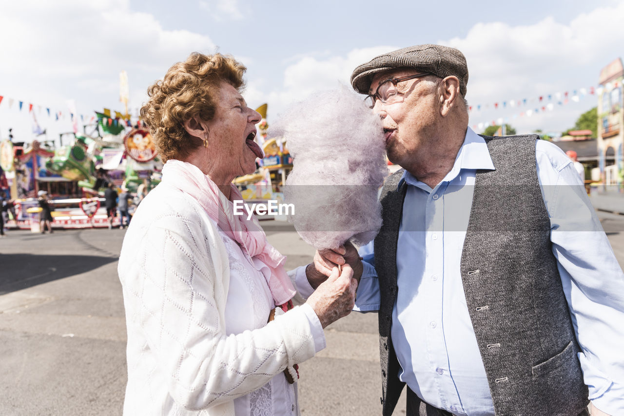 Senior couple on fair eating together cotton candy